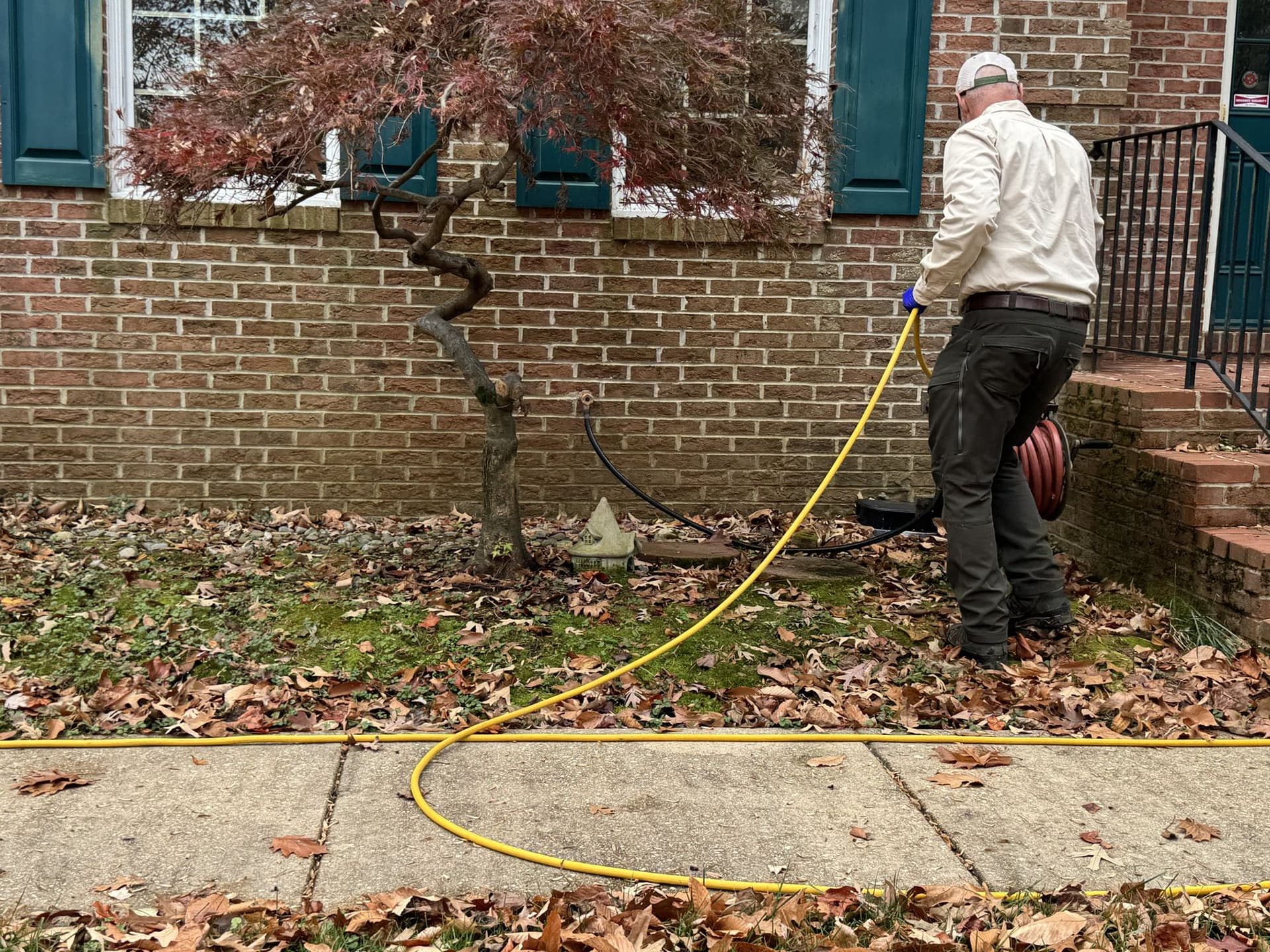 A technician treating along the foundation of a brick home, starting outside