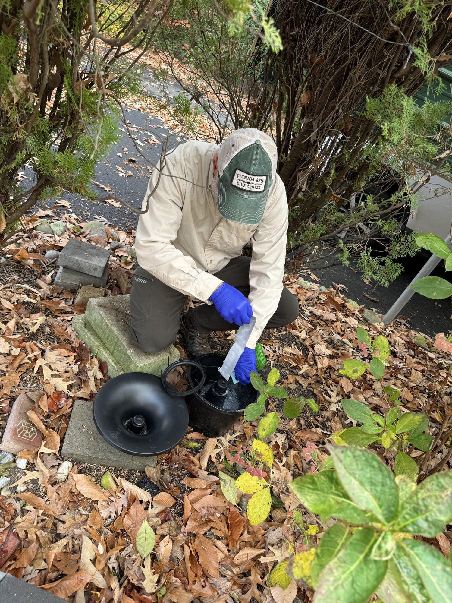 A Planet Friendly technician servicing an in-ground mosquito control station in a yard