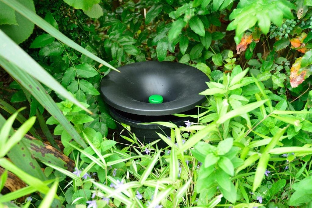 An In2Care mosquito trap placed discreetly in a shaded corner of a backyard