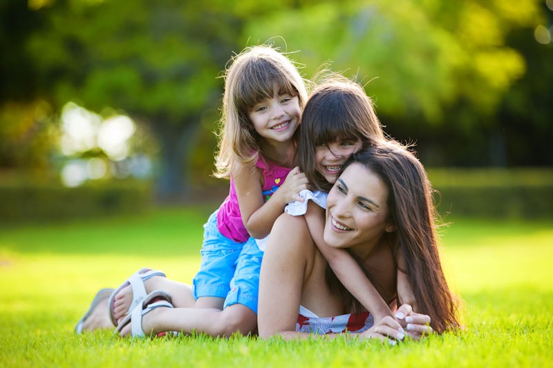 Young mother and two daughters playing in grass